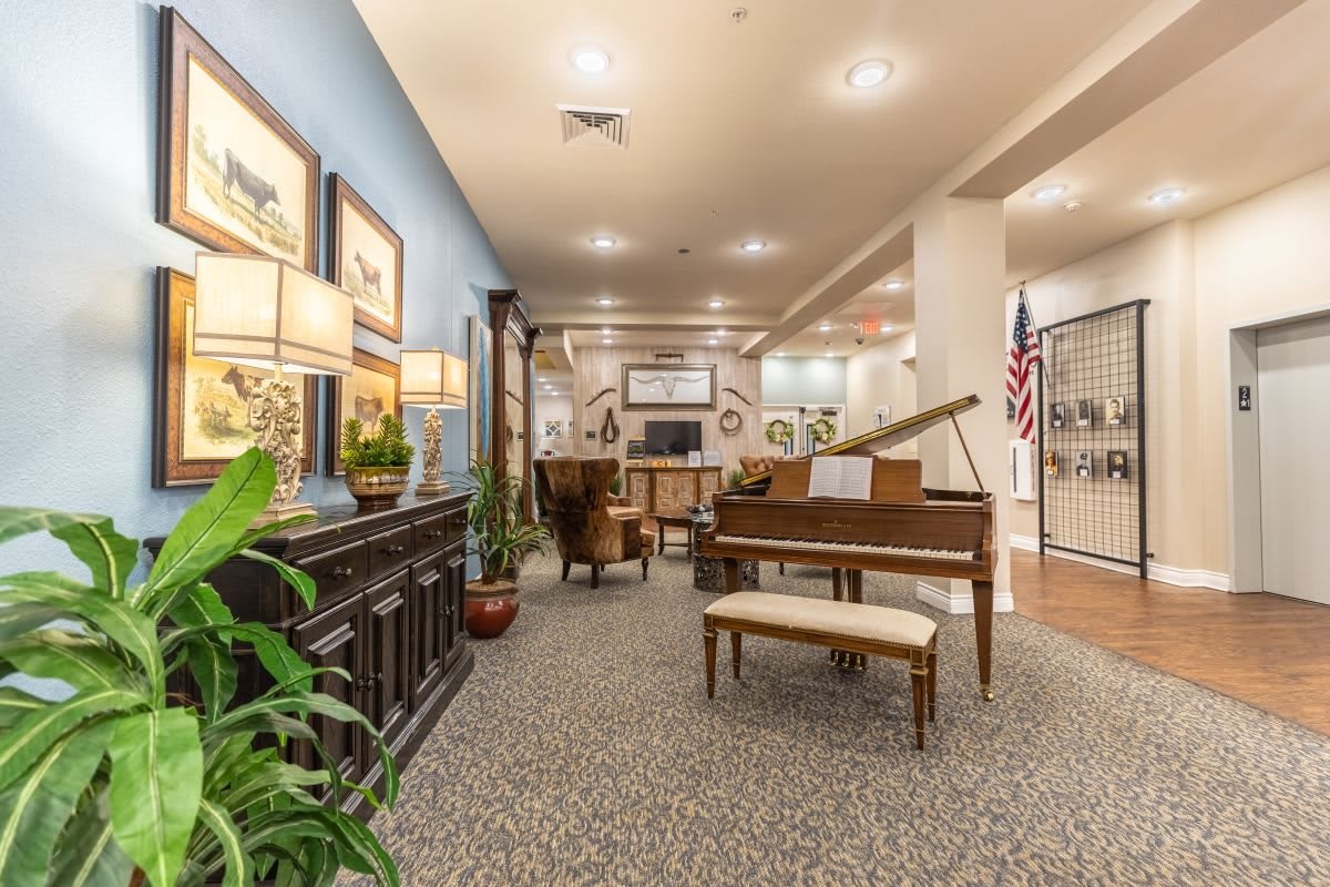 A cozy lounge area featuring a grand piano, surrounded by elegant furniture and artwork.
