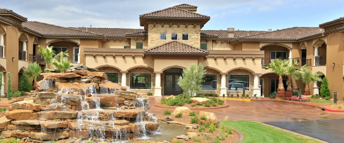 A luxurious home with a beautiful waterfall feature in the front yard.