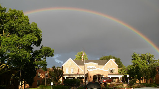 A vibrant rainbow stretches across a gray sky above a charming building.
