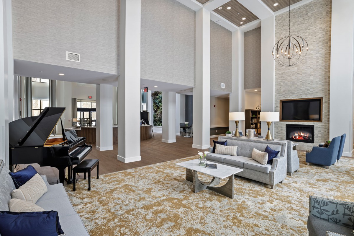 A spacious and luxurious living room with high ceilings, featuring modern furniture and a grand piano.