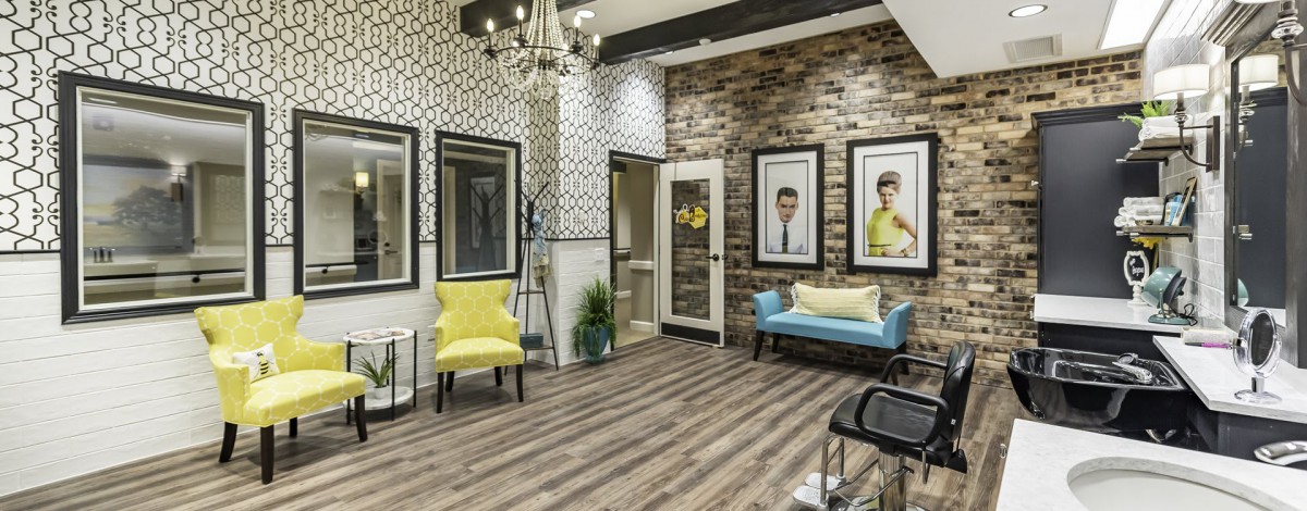 A stylish waiting room featuring a mix of modern and classic design elements, with yellow chairs, a blue sofa, and decorative wallpaper.