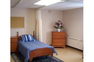 A simple, minimalist bedroom with a single bed and a dresser.