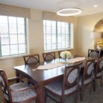 Elegant dining room with a wooden table and chairs, illuminated by modern lighting.