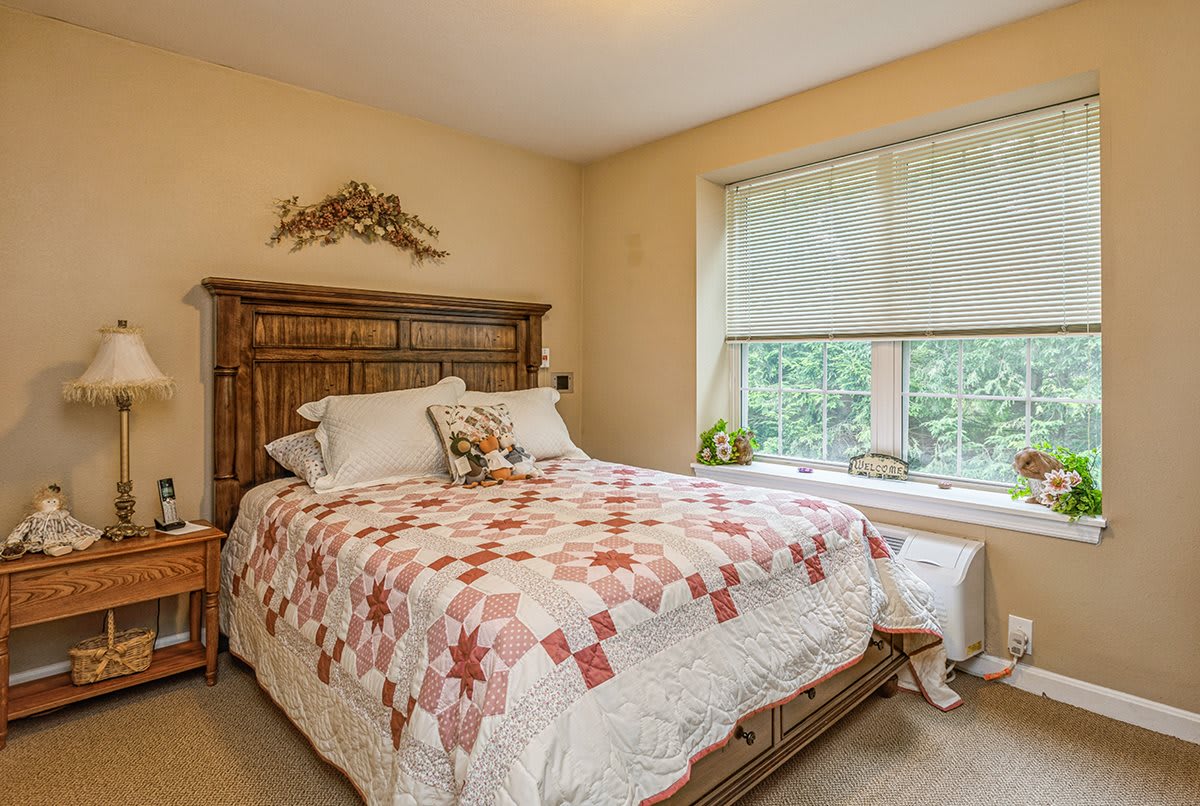A cozy bedroom with a quilt-covered bed and large window.
