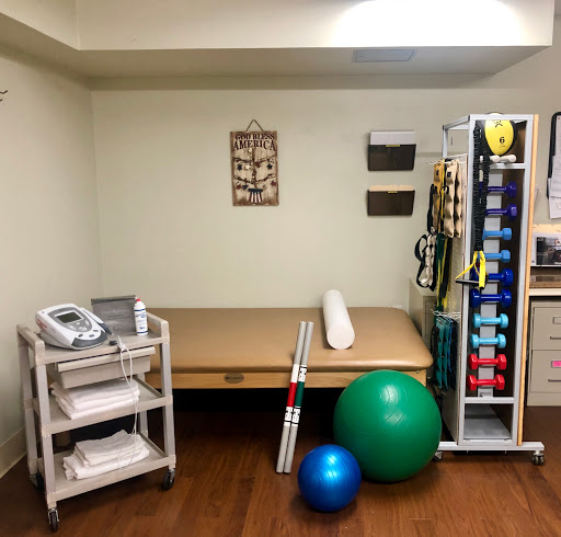 A well-equipped physical therapy room featuring a treatment table, exercise balls, and various medical devices.