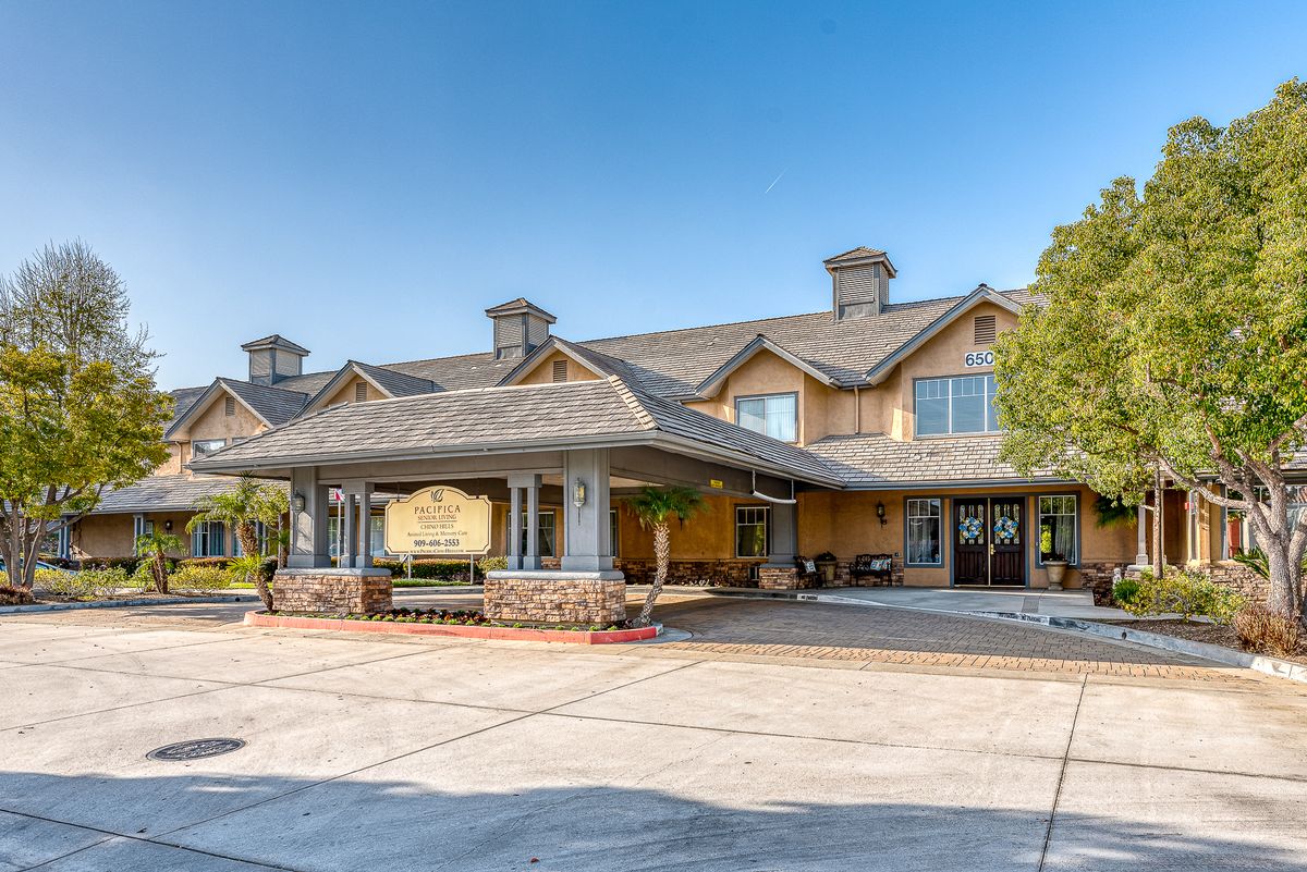 A sunny day view of a large building with a welcoming entrance and parking area.