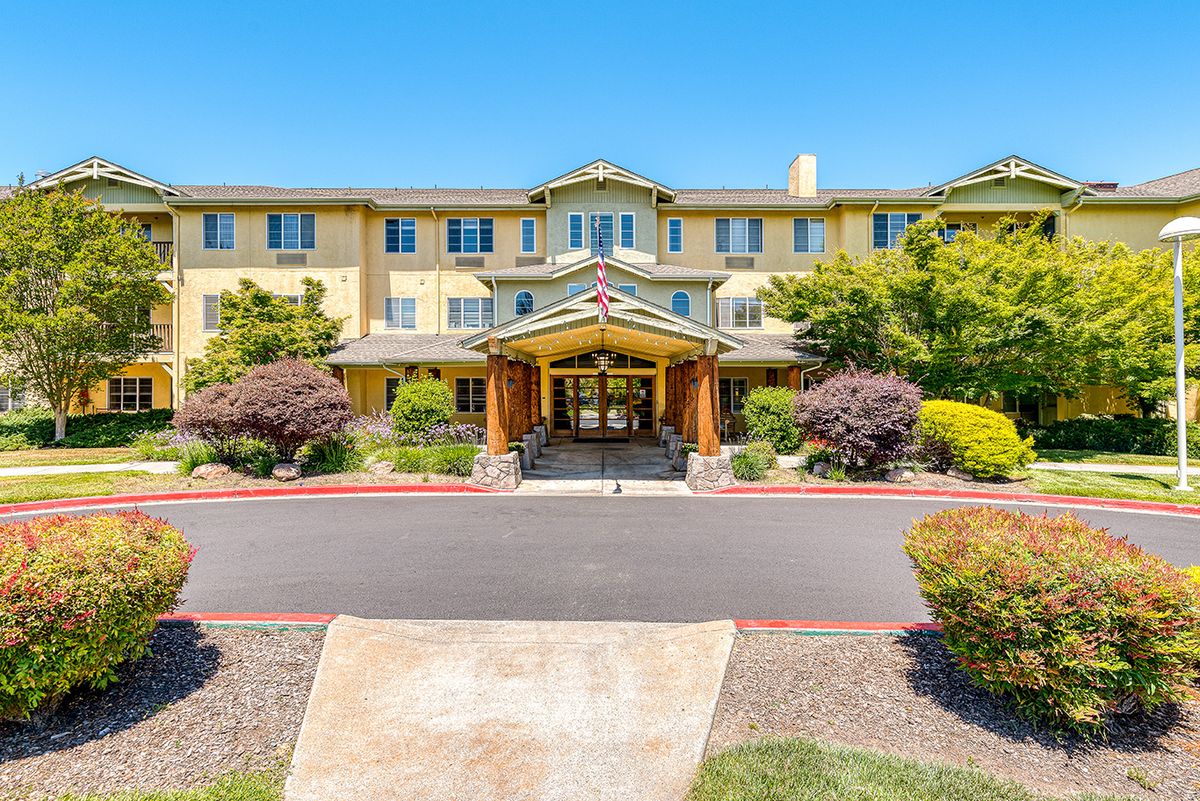 A hotel entrance with well-maintained landscaping and a clear blue sky.