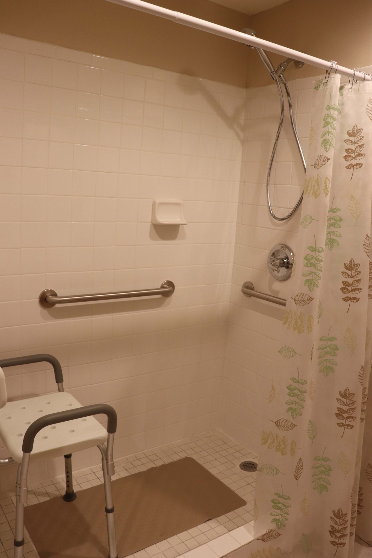 An accessible shower with grab bars and a shower chair.