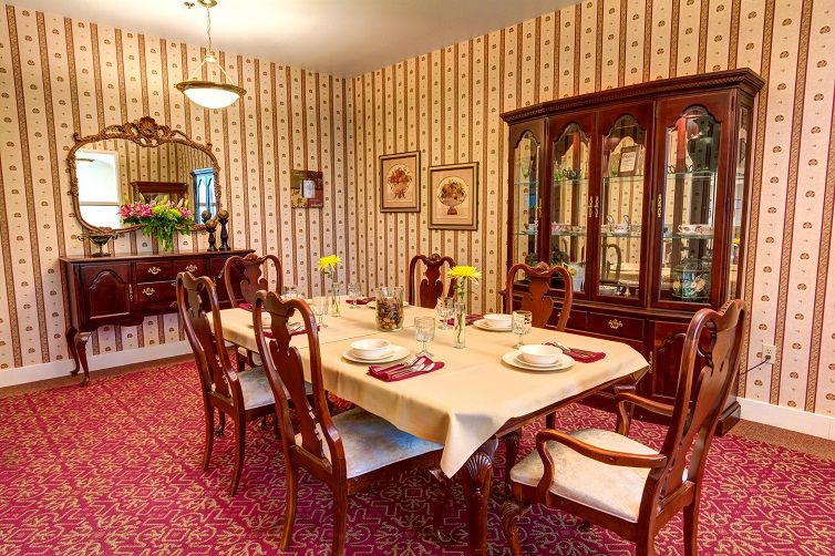 A classic dining room with vintage wallpaper, a set dining table, and elegant wooden furniture.