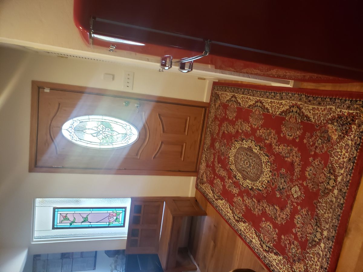 A warmly lit entrance with a decorative carpet and stained glass window.