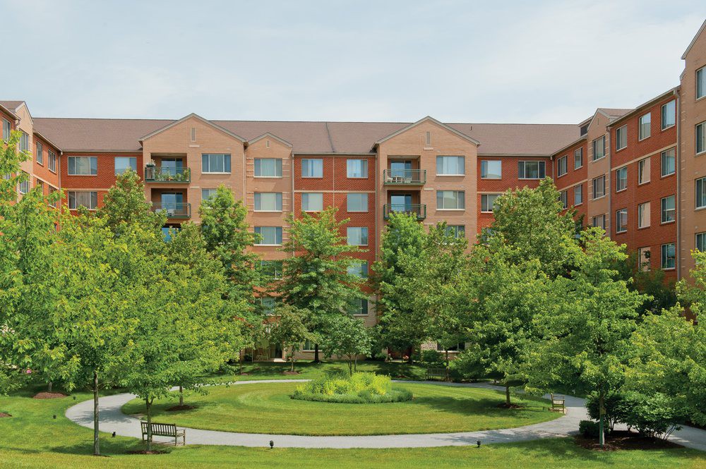 A residential apartment building surrounded by well-maintained landscaping and trees.