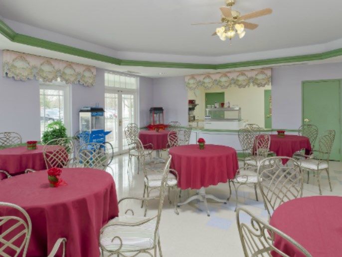 A cozy cafe interior with red tablecloths and metal chairs.
