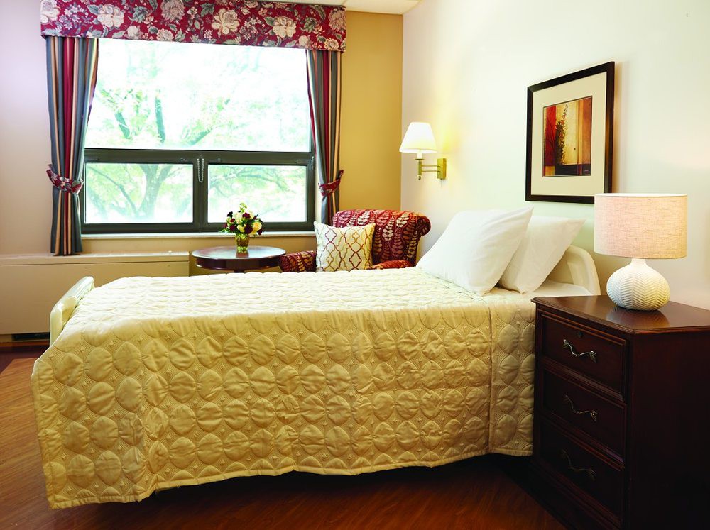 A cozy bedroom with a neatly made bed, a window view, and warm lighting.