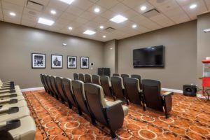 A small theater-style room with rows of seating facing a large screen.