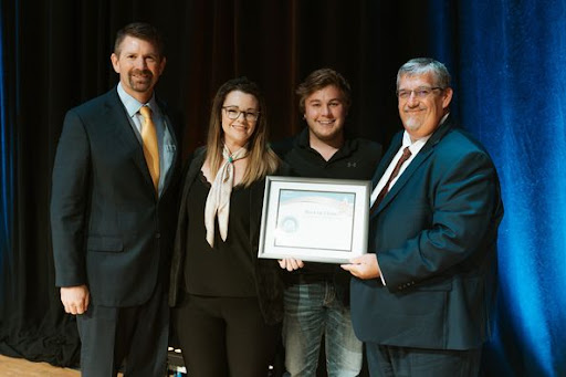 A team is recognized at an awards ceremony, proudly holding a certificate.