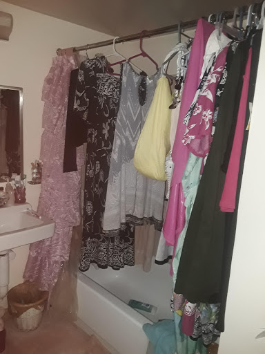 A bathroom scene featuring various garments hanging from rods, showcasing a mix of styles and colors.