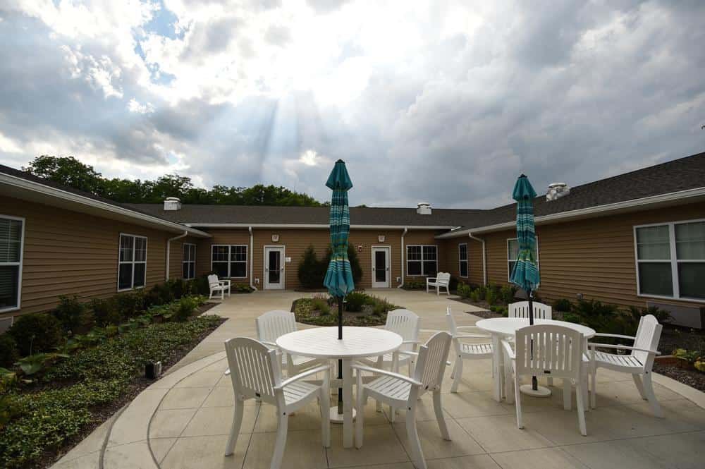 A peaceful patio area with tables, chairs, and umbrellas under a cloudy sky.