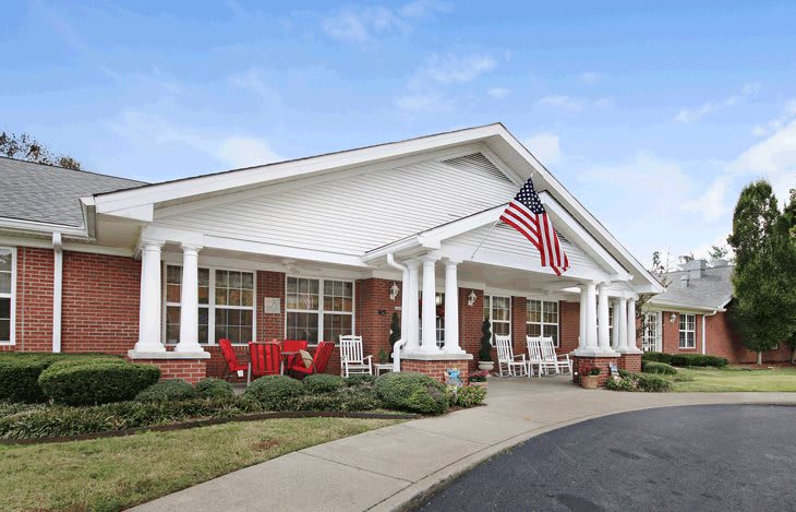 A welcoming building with a front porch, adorned with an American flag and surrounded by well-maintained landscaping.