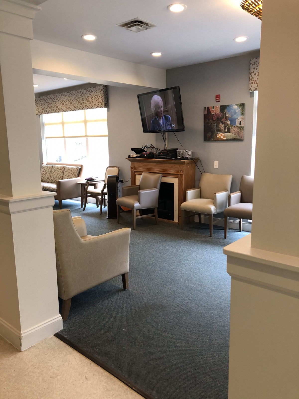 A cozy waiting room with comfortable chairs, a television, and natural light streaming through the window.