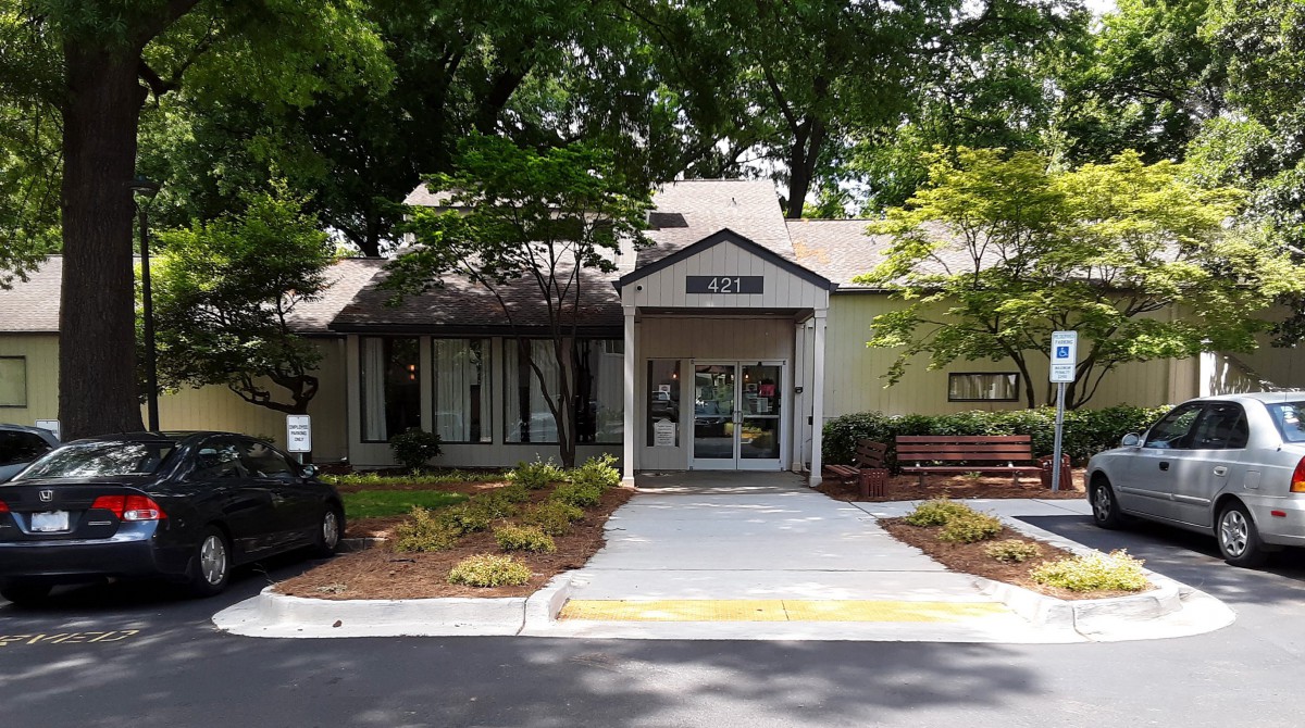 Entrance to a building surrounded by trees and landscaping.