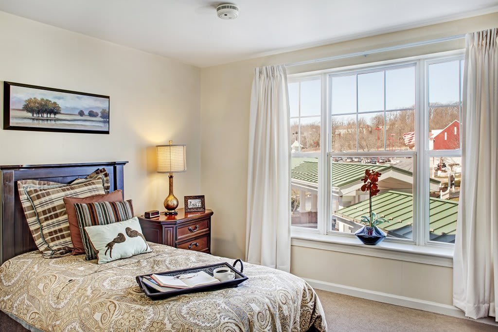 A cozy bedroom with a single bed, nightstand, and large window overlooking a scenic view.