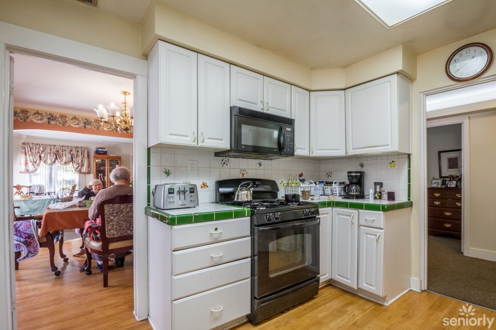 A modern kitchen with white cabinets and green tile backsplash.