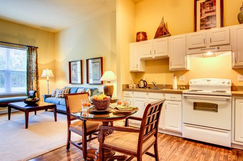 A cozy living space featuring a kitchen, dining table, and sofa in a warmly lit setting.