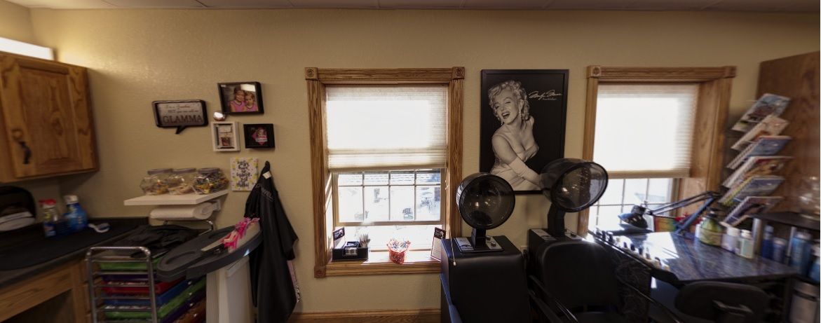 A cozy barber shop interior featuring a window, wall art, and hair dryers.