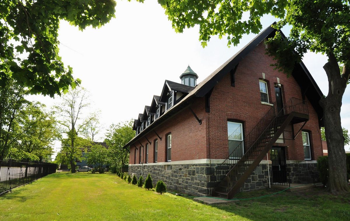 A red brick building surrounded by lush greenery and trees under a clear sky.