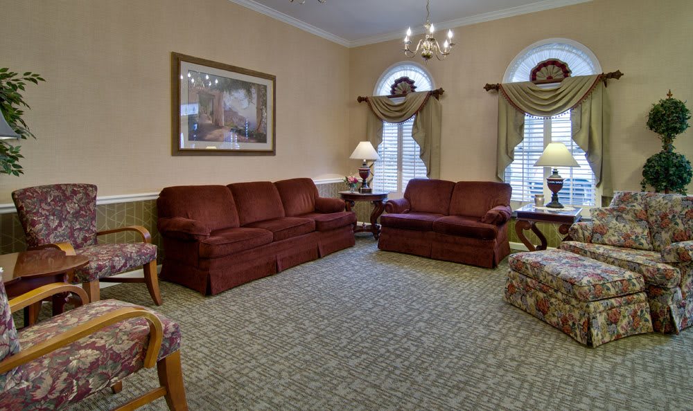 A traditional living room with two brown sofas, a patterned carpet, and a chandelier.