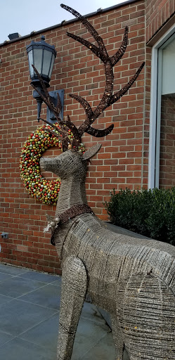 A beautifully crafted deer sculpture adorned with a festive wreath.