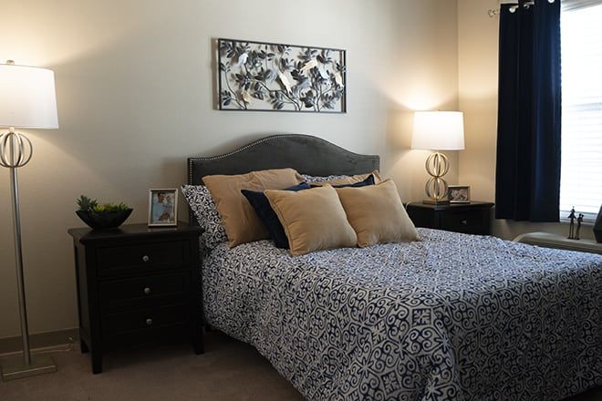 A modern bedroom with a stylish bed, decorative pillows, bedside tables, and a contemporary lamp.