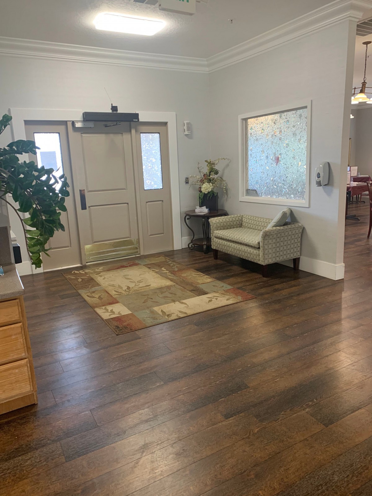 A cozy lobby area featuring a comfortable sofa, a potted plant, and wooden flooring.