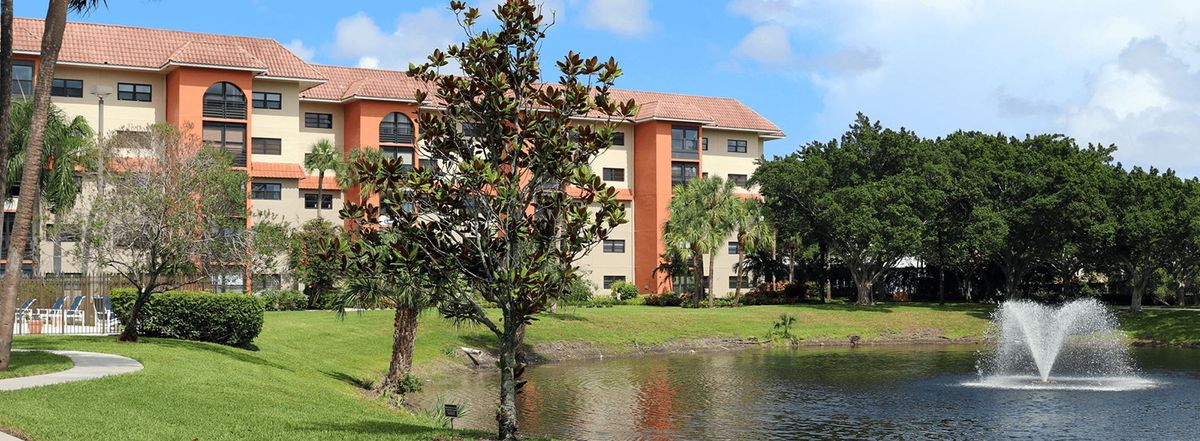 A scenic view of an apartment building surrounded by trees and a lake.