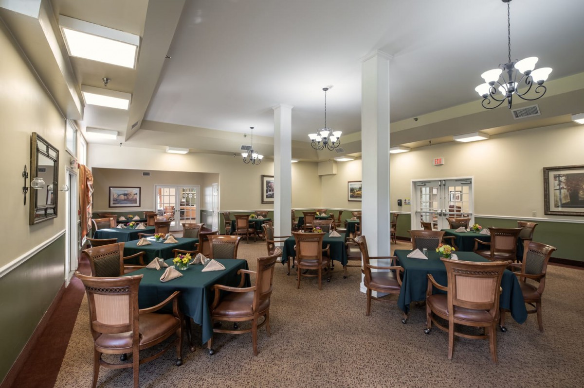 A spacious dining area featuring multiple tables and chairs, with elegant lighting and tasteful decor.
