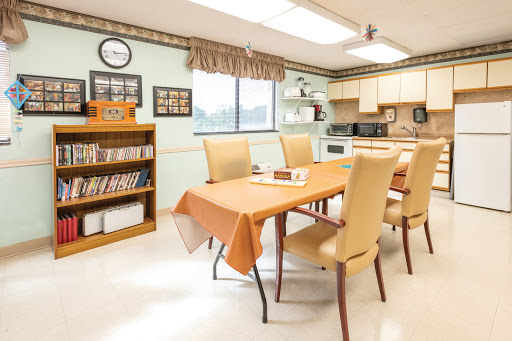 A cozy dining area featuring a table set with chairs, surrounded by shelves and kitchen appliances.
