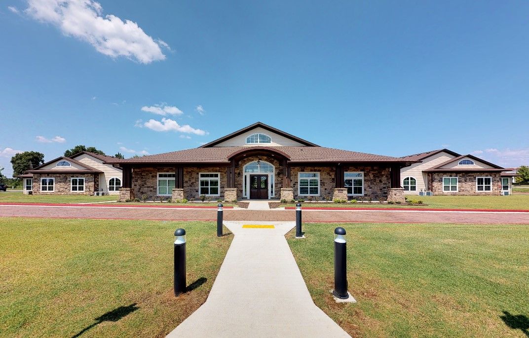 A wide view of a single-story building with a central entrance, surrounded by manicured lawns and under a clear blue sky.