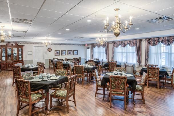 An elegant dining room with chandeliers and neatly arranged tables and chairs.