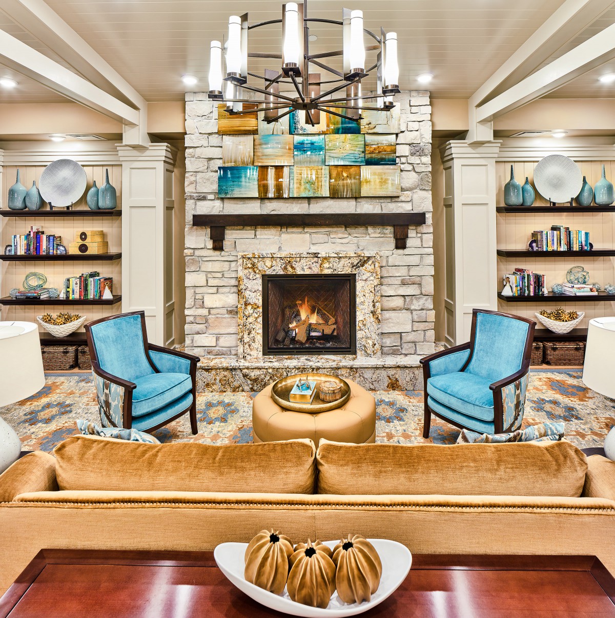 A cozy living room with a stone fireplace, surrounded by bookshelves and elegant furniture.