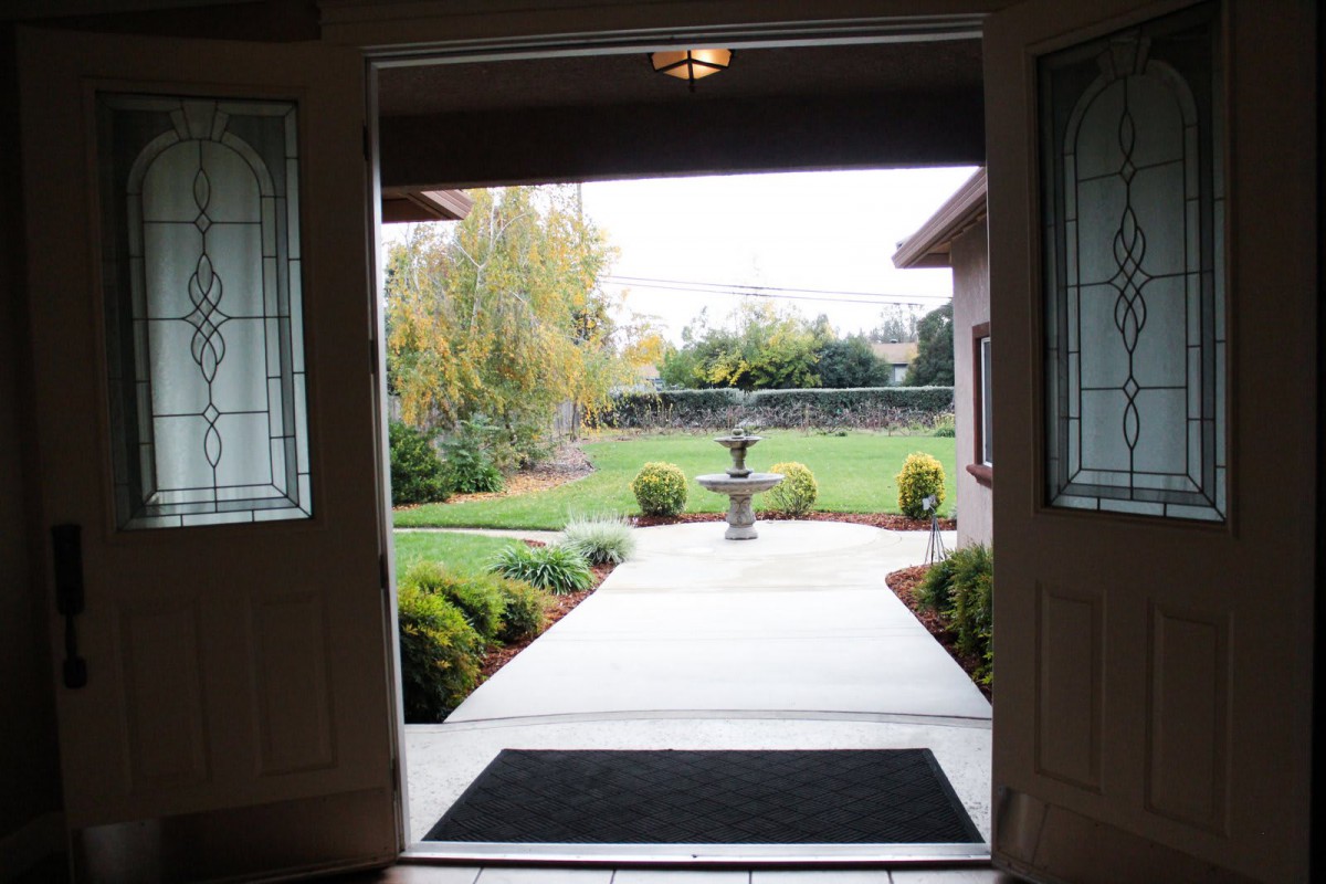 View from an open doorway leading to a landscaped garden with a central fountain.