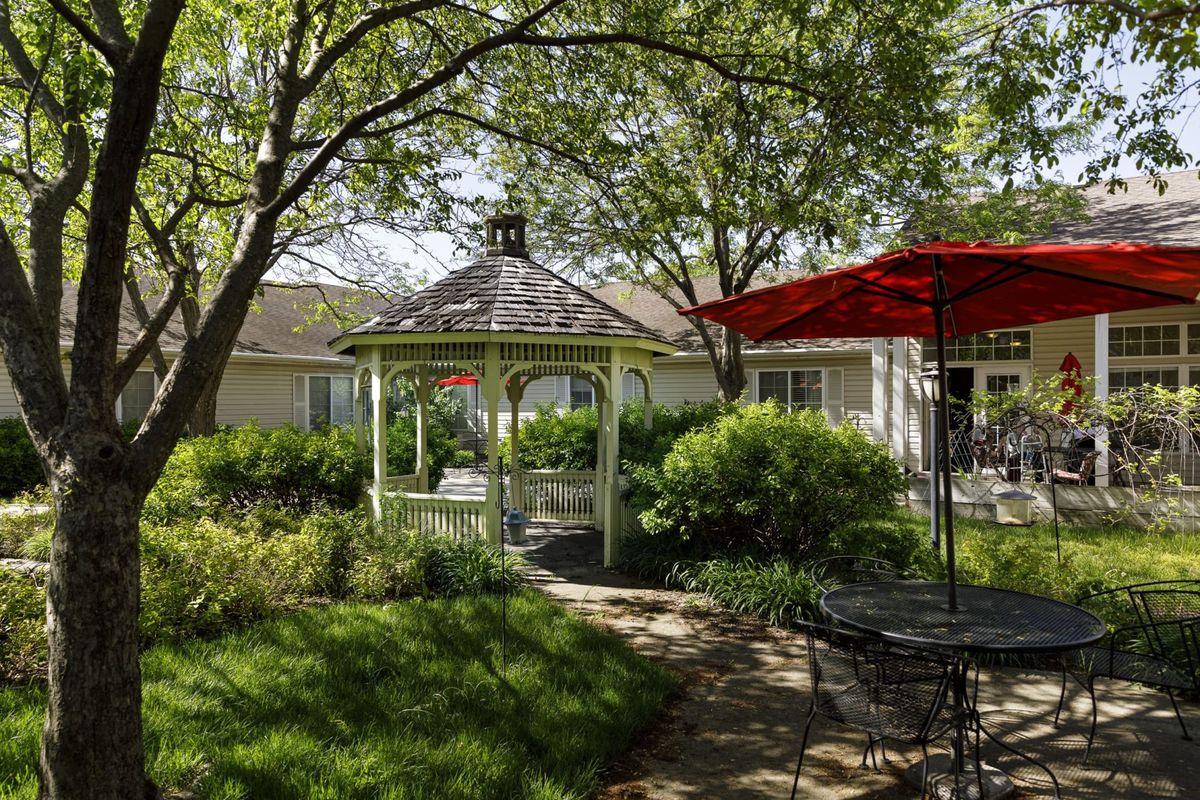 A peaceful garden with a gazebo, surrounded by lush greenery and outdoor seating.