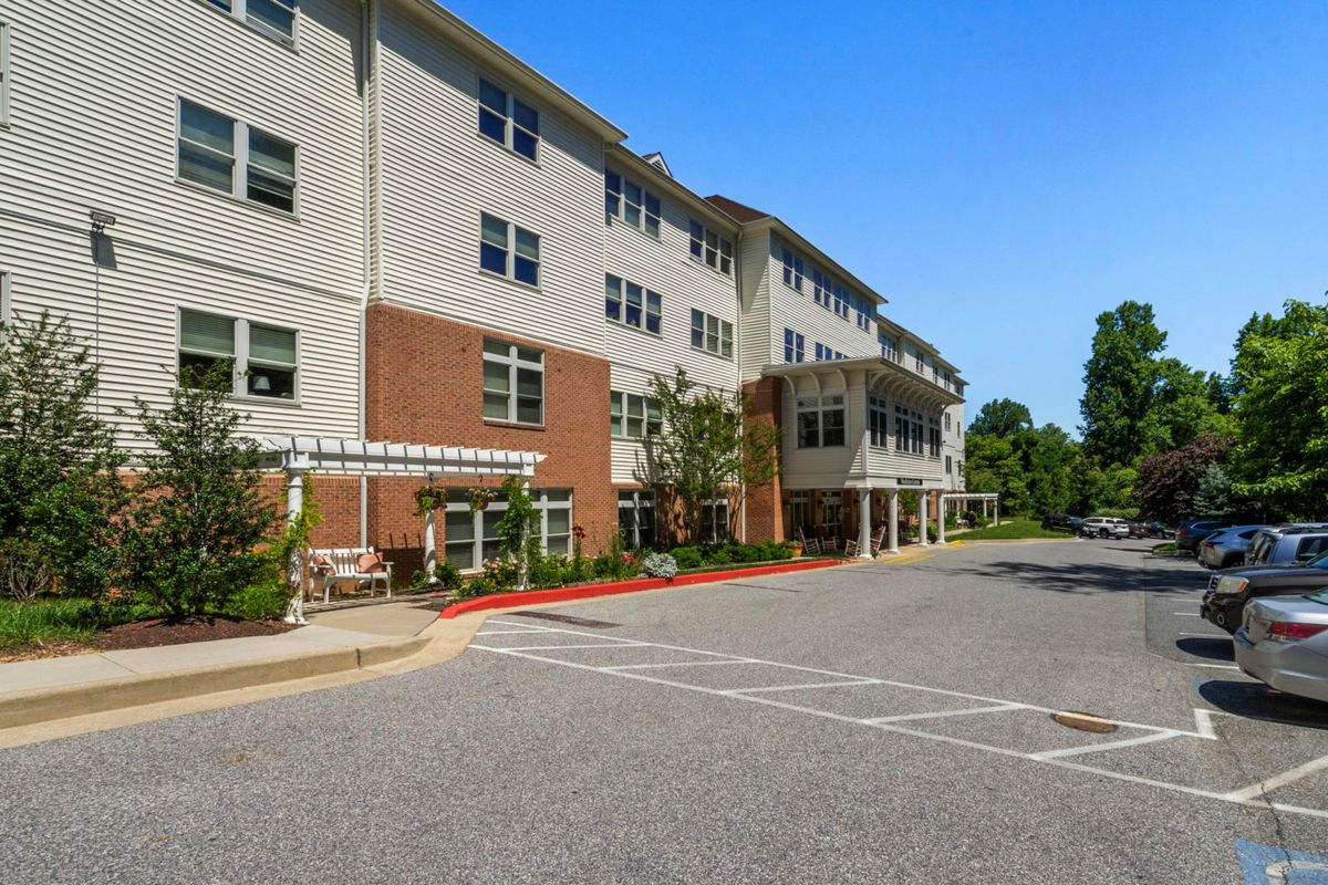 Exterior view of a multi-story residential building with parking area.
