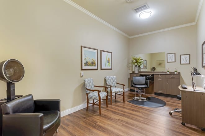 A cozy waiting area with chairs, artwork on the walls, and a small counter with a mirror.