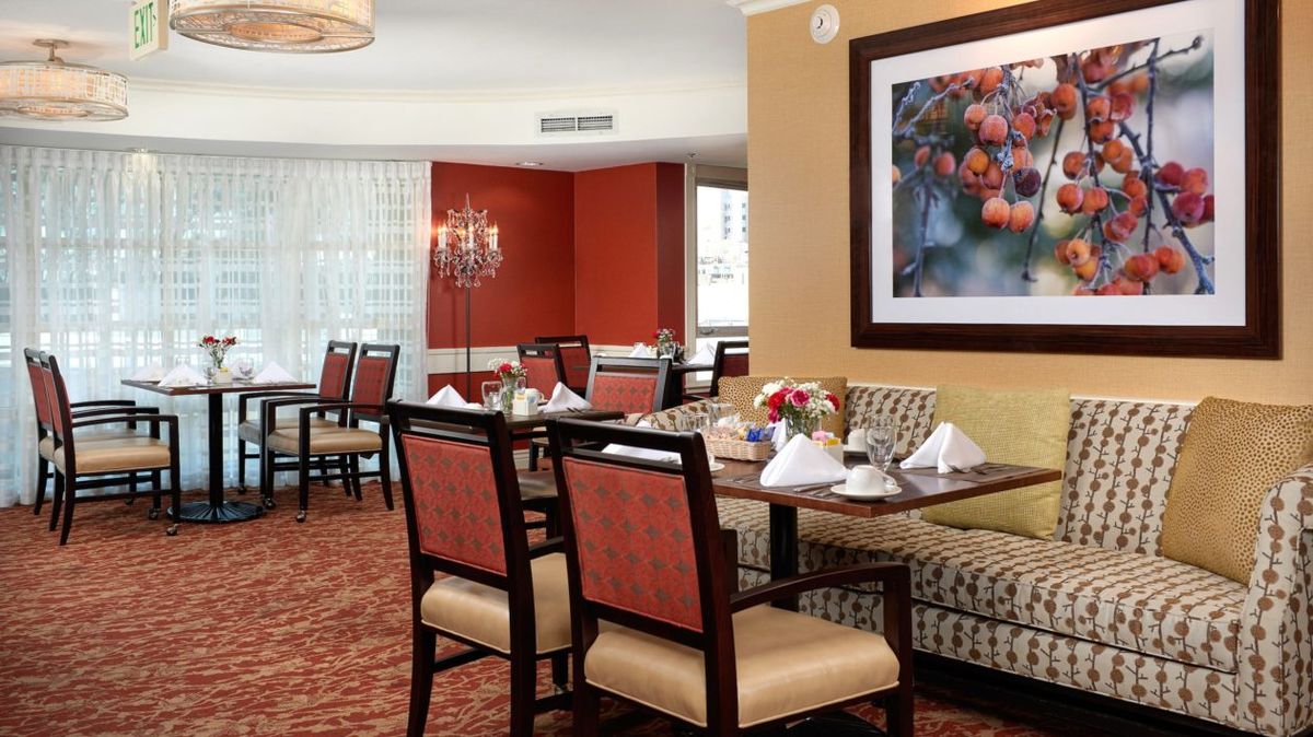 A well-appointed dining area with neatly arranged tables and chairs, featuring tasteful artwork on the wall.