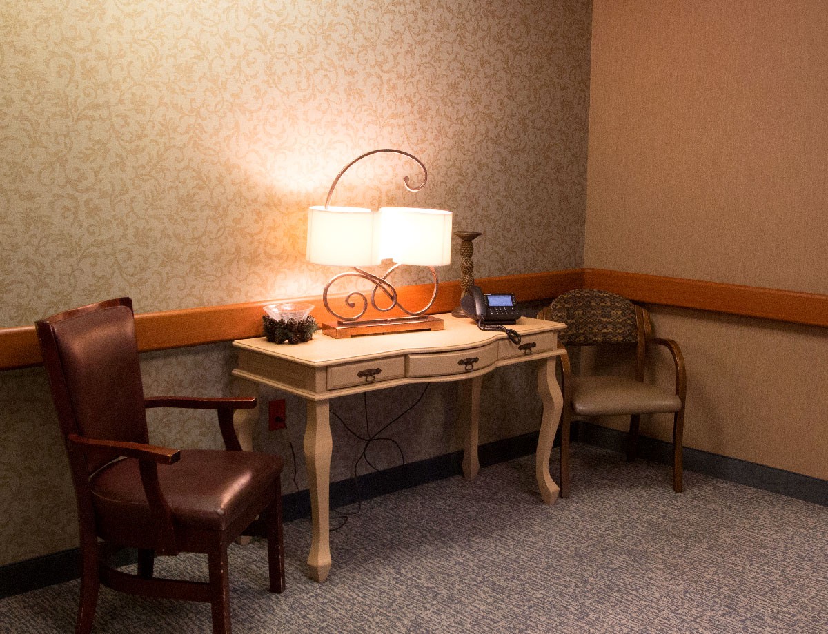 A quiet waiting room corner with a desk, two chairs, and a decorative lamp.