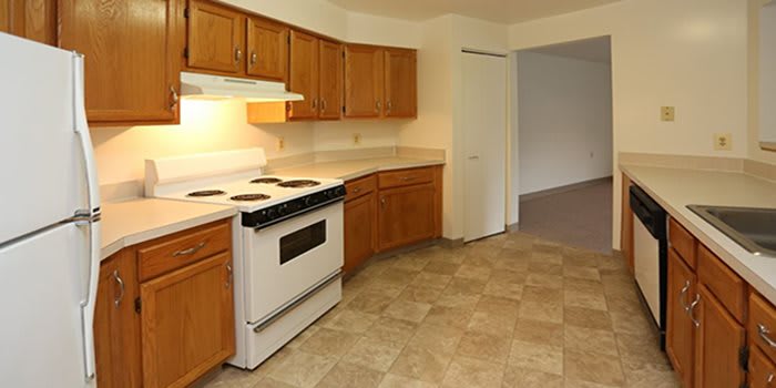 A kitchen interior featuring wooden cabinets, a white stove, and tiled flooring.