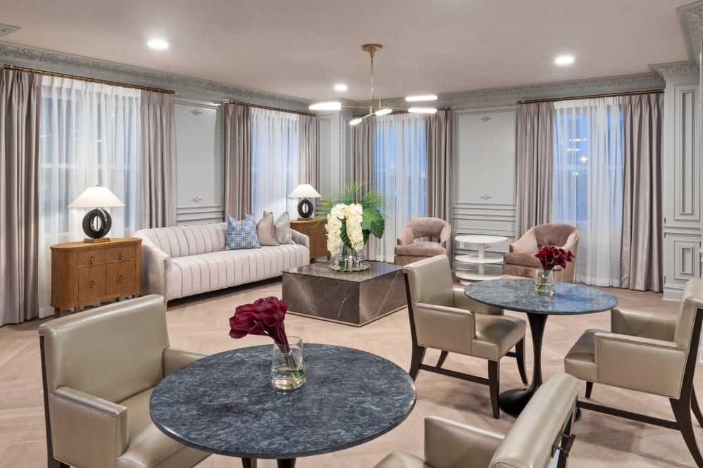 A cozy and elegantly designed living room with sofas, chairs, and floral decor.