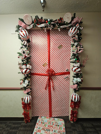 A beautifully decorated door that resembles a giant gift, complete with festive garlands and ornaments.