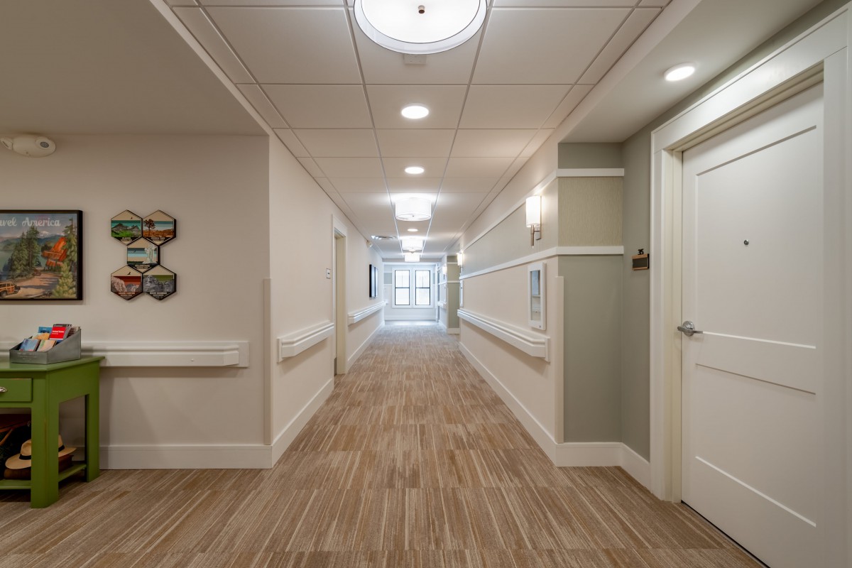 A well-lit hallway in a building with wooden flooring and multiple doors.