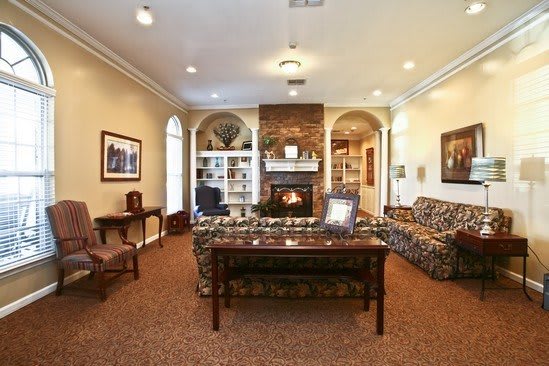 A cozy living room with a central fireplace, surrounded by comfortable furniture and decorative shelves.